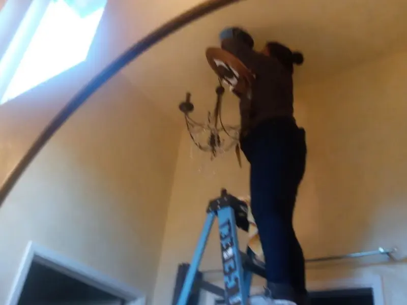 Electrician installing a chandelier in a Corinth residence